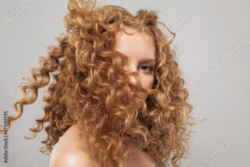Glamorous wavy hair woman. Young fashion model with long curly hairstyle and natural fresh clear skin posing on white background