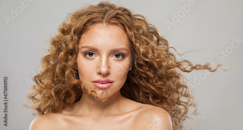 Magnificient wavy hair woman. Young fashion model with long curly hairstyle and natural fresh clear skin posing on white background