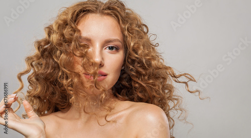 Redhead wavy hair woman. Young fashion model with long curly hairstyle and natural fresh clear skin posing on white background