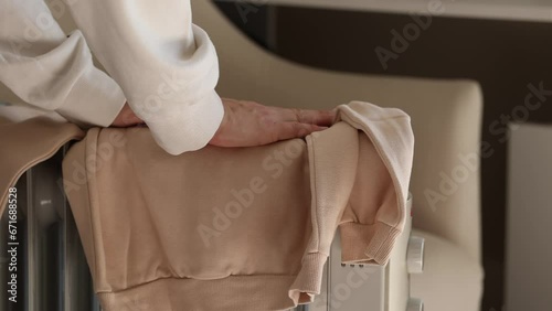 Mom puts the children's clothes on the electric radiator in the cold morning to warm .The concept of saving electricity, the energy crisis. A woman's care for her children in the season of colds