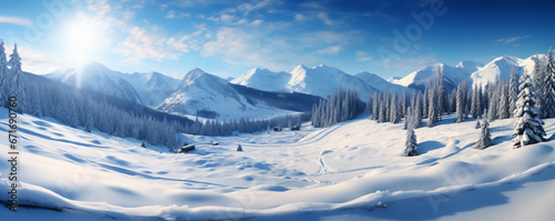 Panoramic view of a snowy mountain range. The mountains are covered in snow and the valley is surrounded by trees. The sky is a clear blue and there are a few clouds in the distance. photo