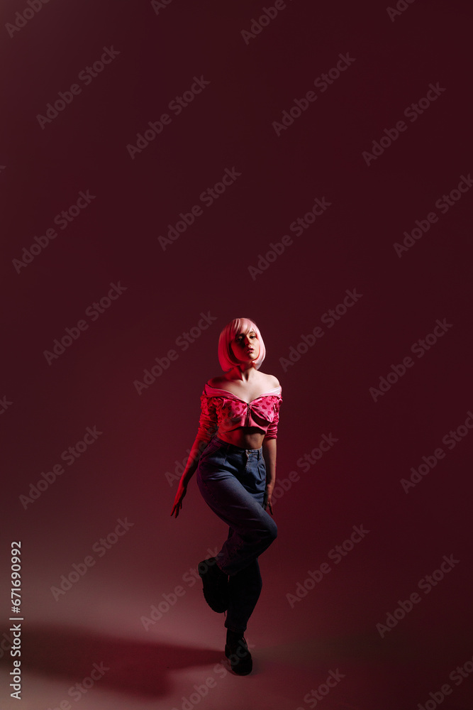Stylish woman with pale pink hair wearing a pink jacket and jeans poses confidently against a pink background. Fashion advertising concept, individuality and confidence.