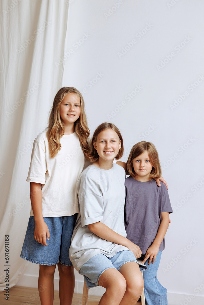 Caucasian teenagers happy girls in casual clothes laugh together. Portrait of three sisters hugging.