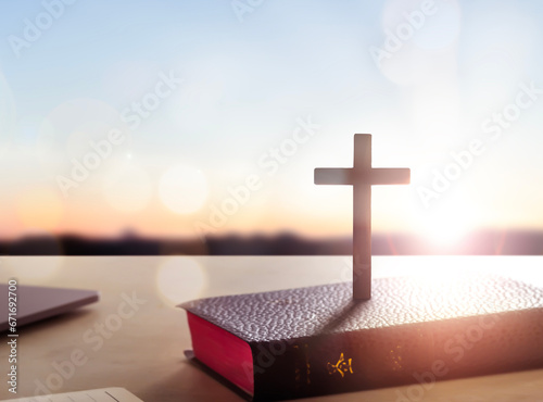 Silhouette wooden cross on holy bible sunset background
