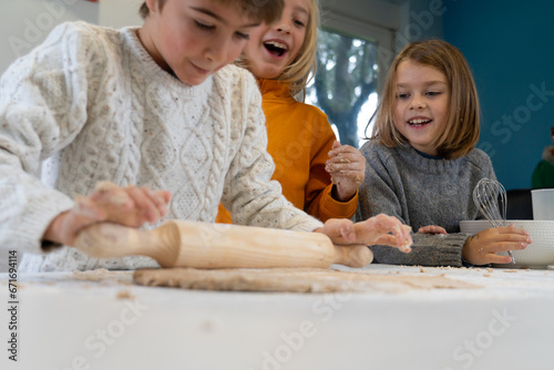 Children kneading homemade pizza dough in the kitchen at home