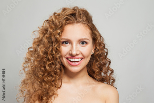 Young happy laughing woman redhead fashion model with long natural healthy brown curly hair and cute smile having fun on white background, studio portrait