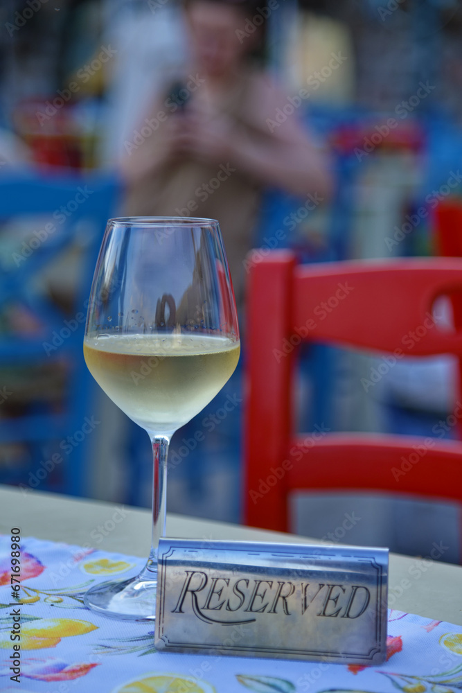 Glass of white wine and sign of reservation at table in restaurant