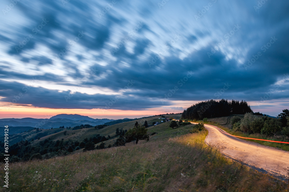 Light trails from a car on a mountain road at sunset