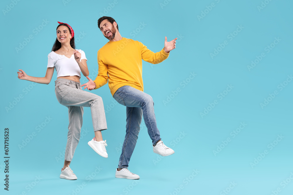 Happy couple dancing together on light blue background, space for text Happy couple dancing together on light blue background, space for text