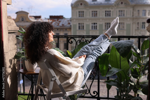 Fotobehang Beautiful young woman relaxing in chair surrounded by green houseplants on balco