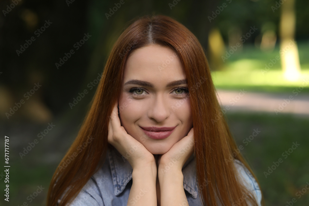 Portrait of beautiful young woman with red hair outdoors. Attractive lady looking into camera Portrait of beautiful young woman with red hair outdoors. Attractive lady looking into camera