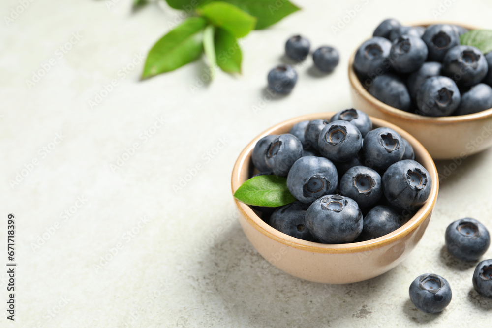 Tasty fresh blueberries in bowls on light grey table, closeup. Space for text Tasty fresh blueberries in bowls on light grey table, closeup. Space for text