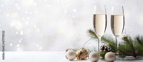 Two glasses of champagne adorned with pine branches festive ornaments symbolizing Christmas and the New Year beautifully embellish a white wall in the background