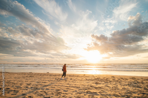 Man, a traveler watching a breathtaking sunset on the shores of the North Sea near Zandvoort, Netherlands. Abstract view of the sea surface and the colorful sky