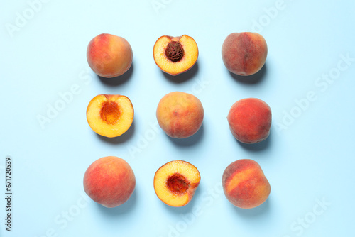 Cut and whole fresh ripe peaches on light blue background, flat lay