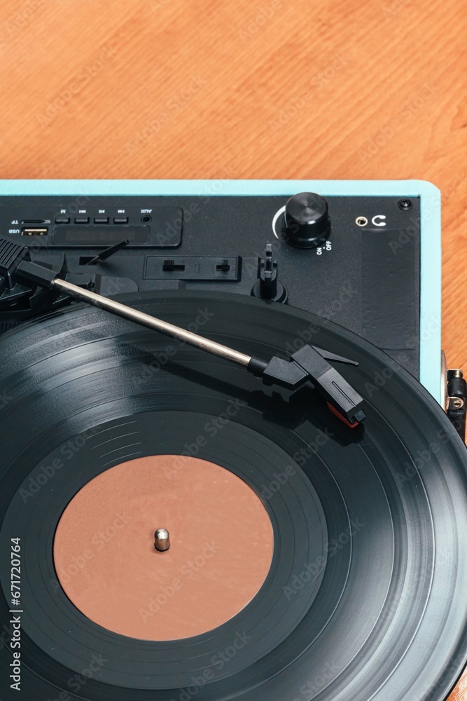 Obraz premium Vertical photo of a blue record player, on wooden table. Concept hobbies, art.