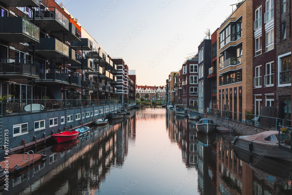 Colourful apartment blocks reflecting on the water surface of the canal that crosses the buildings. Dutch housing. House lifestyle