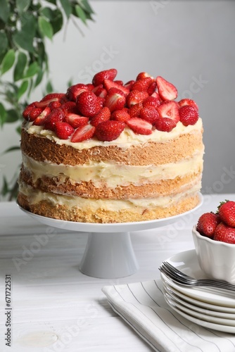 Tasty cake with fresh strawberries served on white wooden table