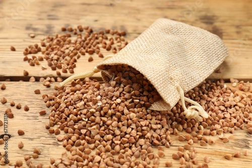 Bag with dry buckwheat on wooden table, closeup
