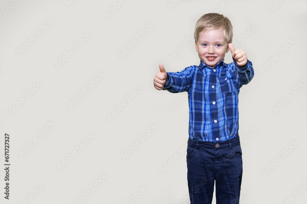 Boy holding thumbs up and smiling, gray background with space for text Boy holding thumbs up and smiling, gray background with space for text