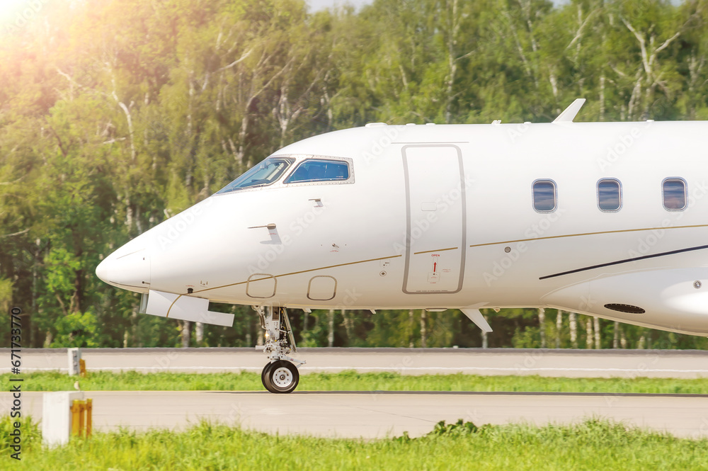 Close-up of the nose of a white passenger private business jet on the taxiway at the airport. The business jet is preparing to take off Close-up of the nose of a white passenger private business jet on the taxiway at the airport. The business jet is preparing to take off