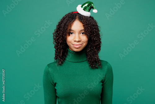 Merry smiling happy cheerful fun cool little kid teen girl wear turtleneck hat casual clothes posing looking camera isolated on plain green background studio portrait. Happy New Year holiday concept.