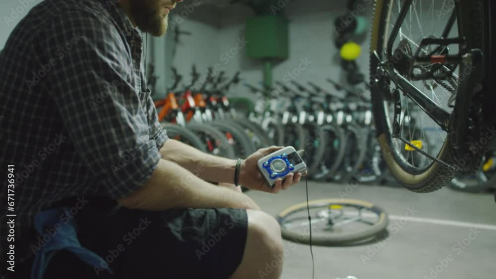 Side view of man putting on headphones and listening to music on portable cassette player while resting at work in bike repair shop