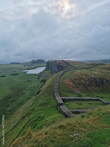 Hadrian,s Wall and Sycamore gap with the tree still standing on a cloudy day on a hiking and wild camping trip photo