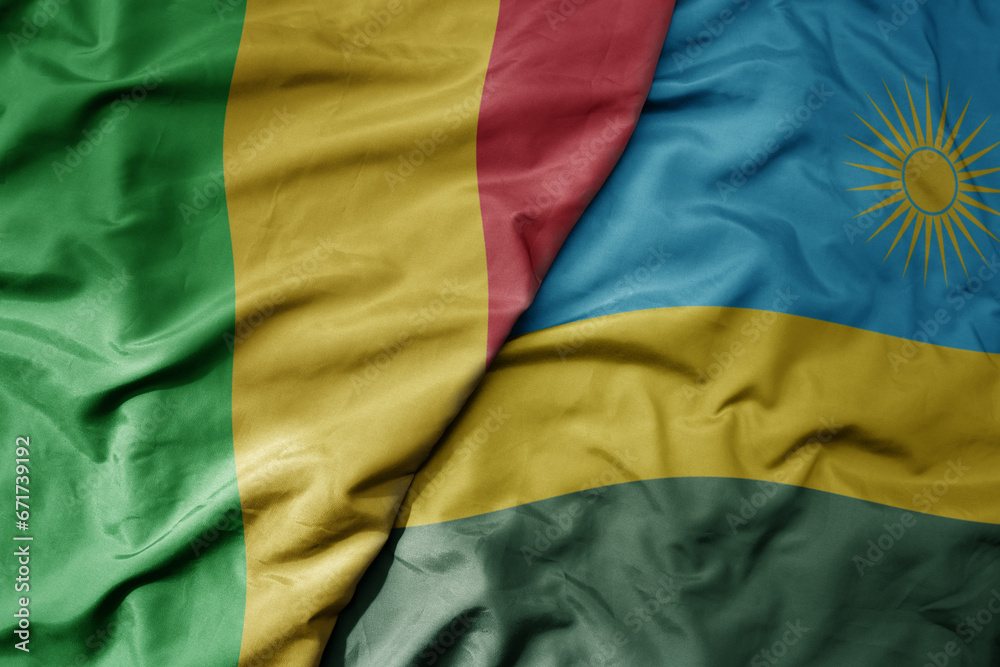 big waving national colorful flag of mali and national flag of rwanda .