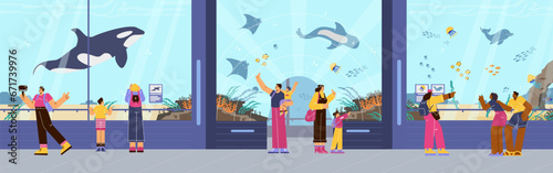 People looking at sea flora and fauna in big tank in oceanarium.