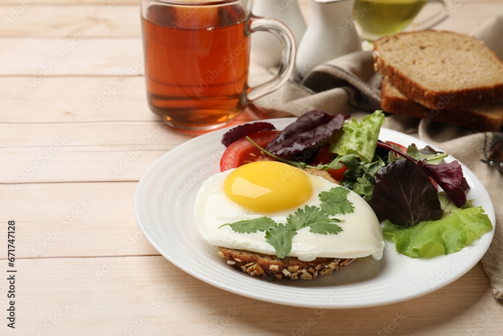 Delicious breakfast with fried egg and salad served on light wooden table. Space for text