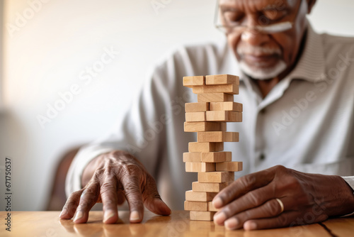 African American Senior man with dementia playing with wooden blocks in geriatric clinic or nursing home photo