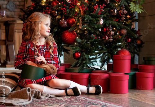 girl with a rabbit at home by the Christmas tree. Christmas concept