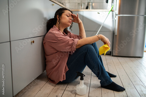 Exhausted woman takes a moment's rest after cleaning in the kitchen photo