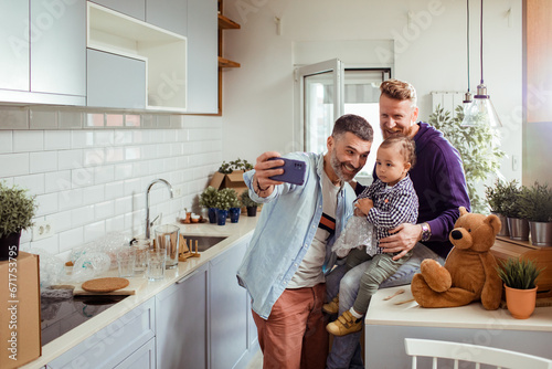 Gay couple capturing a selfie moment with their toddler in their new home photo