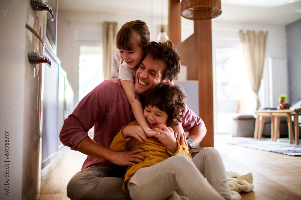 Happy young dad having fun with his kids on the floor at home