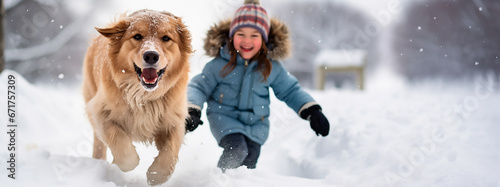 perro labrador y una niña contenta jugando y corriendo hacia la cámara sobre la nieve 