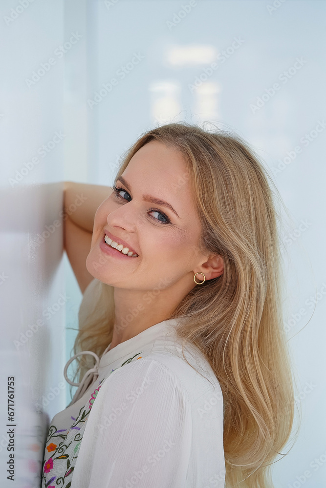 Portrait of attractive smiling young blonde woman with perfect smile. Pretty healthy young female with light natural face makeup inside white interior.