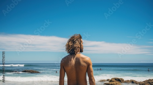 Lonely man surfer holding surfboard on the sunny day beach. AI generated image © orendesain99