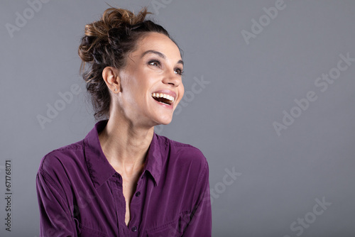 Happy young girl wears a lilac shirt and smiles cheerfully. Emotional female