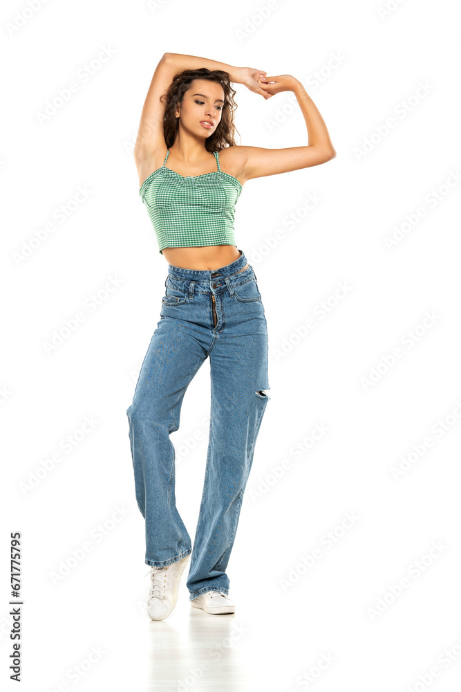 Full length shot of young smiling woman wearing green shirt and blue jeans while posing at isolated white background. Full length shot of young smiling woman wearing green shirt and blue jeans while posing at isolated white background.