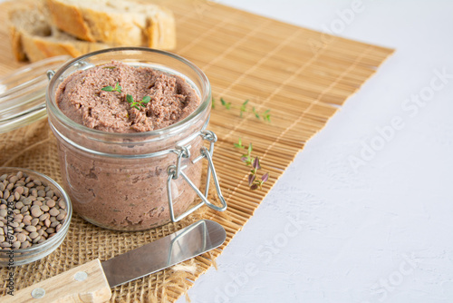 Vegan spread made with lentils and nuts on a rustic bread slice and in a glass jar, decorated with rosemary. Copy space on right side. Vegan dipping.
