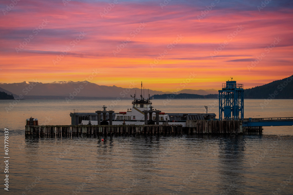 Ferry boat docking at an island in the Salish Sea during a dramatic sunrise. The Whatcom Chief services Lummi Island commuters traveling to the mainland. Washington, USA