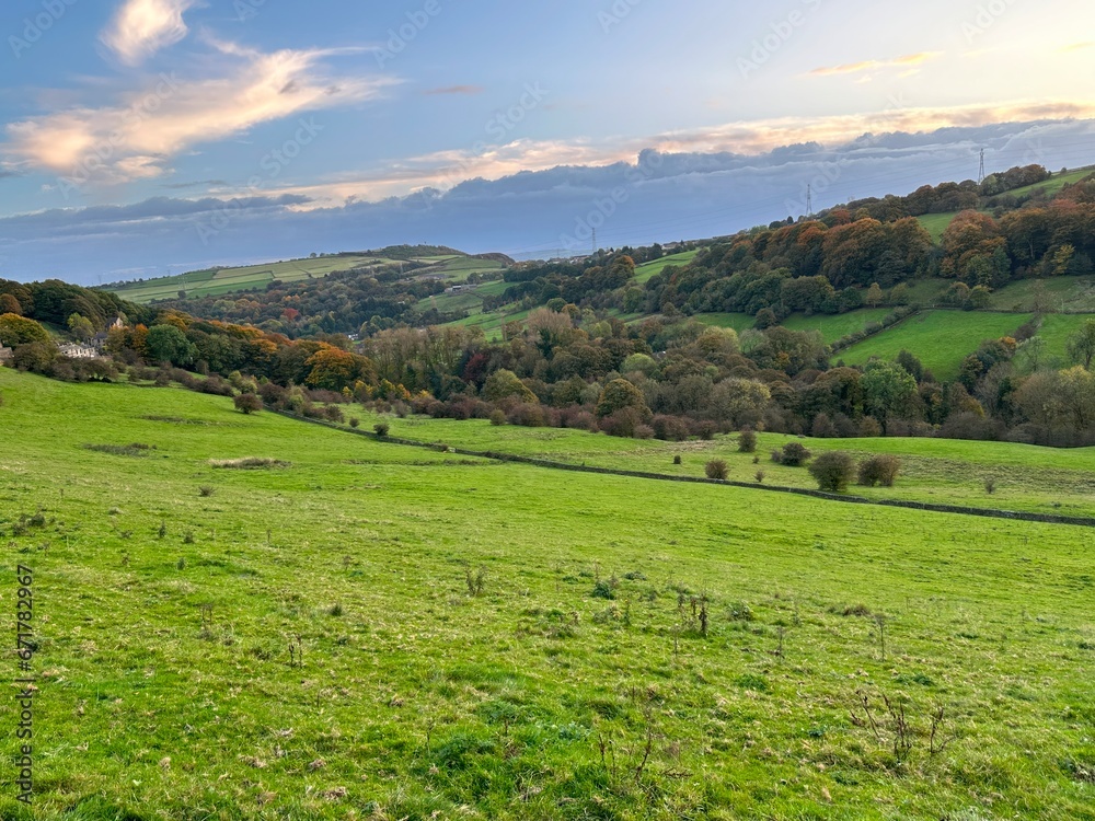 Autumn colours in, Shibden Valley, with sloping fields, farms, houses, and distant hills near, Halifax, UK