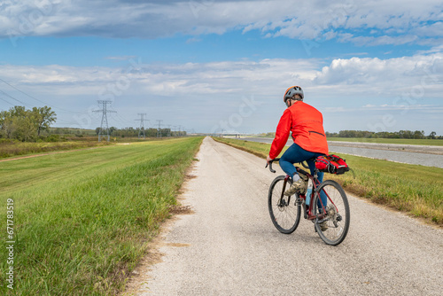 male cyclist is riding a gravel touring bike - biking on a levee trail along Chain of Rocks Canal near Granite City in Illinois