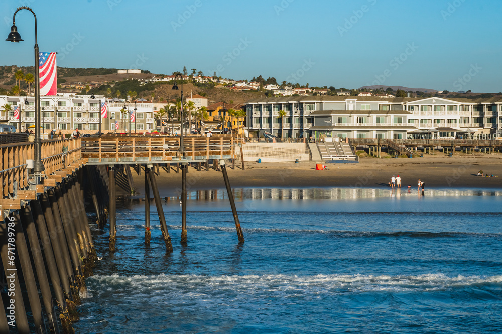 An iconic Pismo Beach pier at sunset. People are enjoying a nice walk and an amazing ocean view