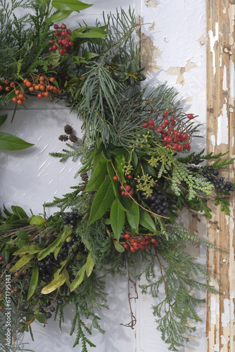 Christmas wreath of green branches and fruits of shrubs on the old white doors, fragment, fragment