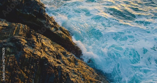 The untouched beauty of nature. The ability of the ocean to self-heal and self-purification of the waters of the world. Unpolluted environment. Splashing water on rocks at sunset in slow motion.