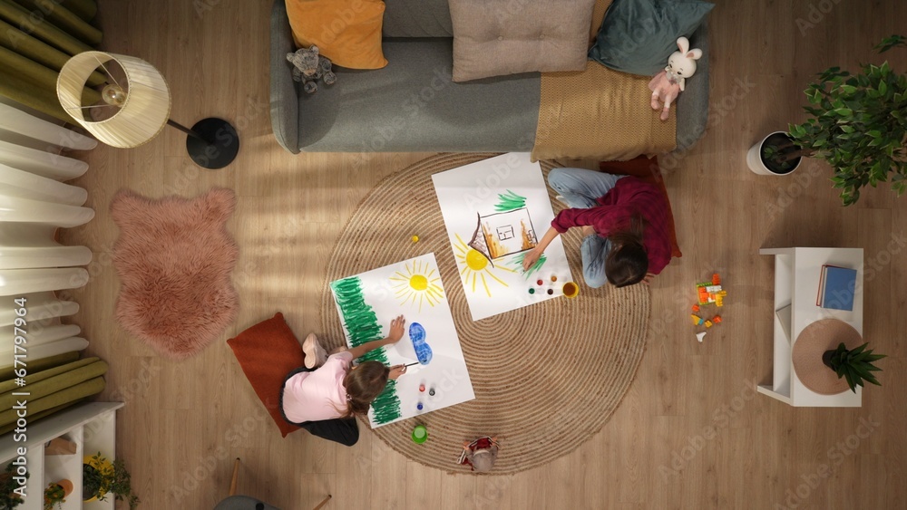 Φωτογραφία In the picture from above sit on the floor of a woman and the child they draw on the sheets of each their own
