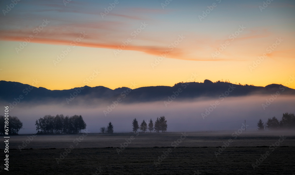 Fototapeta premium Dramatic sunrise over rural farmland with ground fog adding atmosphere. Morning in the Skagit Valley is an almost magical event as the color and texture make for a beautiful landscape. Washington, US